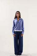 Woman wearing a blue striped shirt and navy pants on a white background