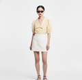 Woman wearing a yellow blouse and white skirt on a white background ishq e amore