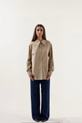 Woman wearing a beige shirt and dark blue pants on a white background